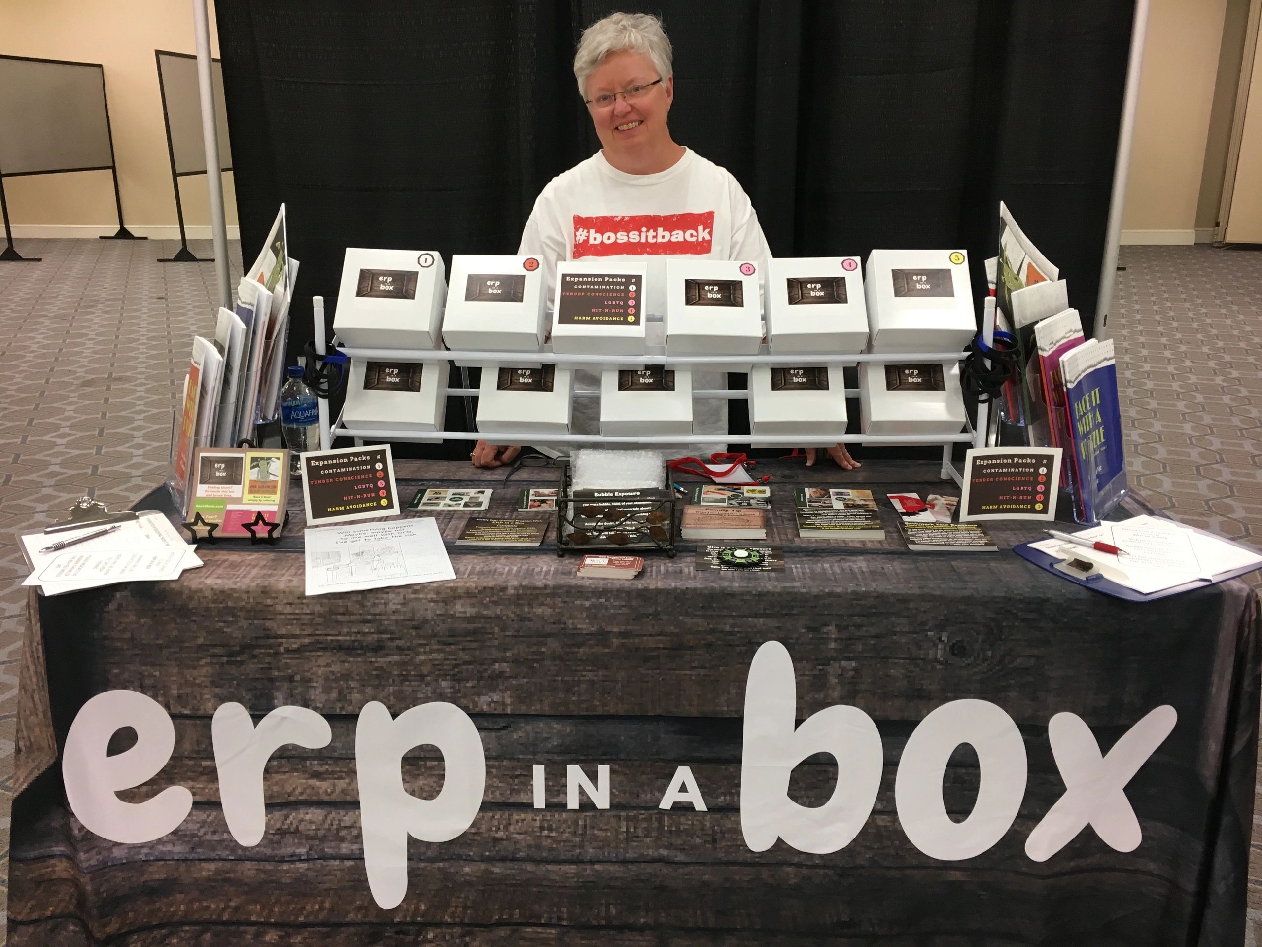 Person promoting "erp in a box" with game boxes at a booth.
