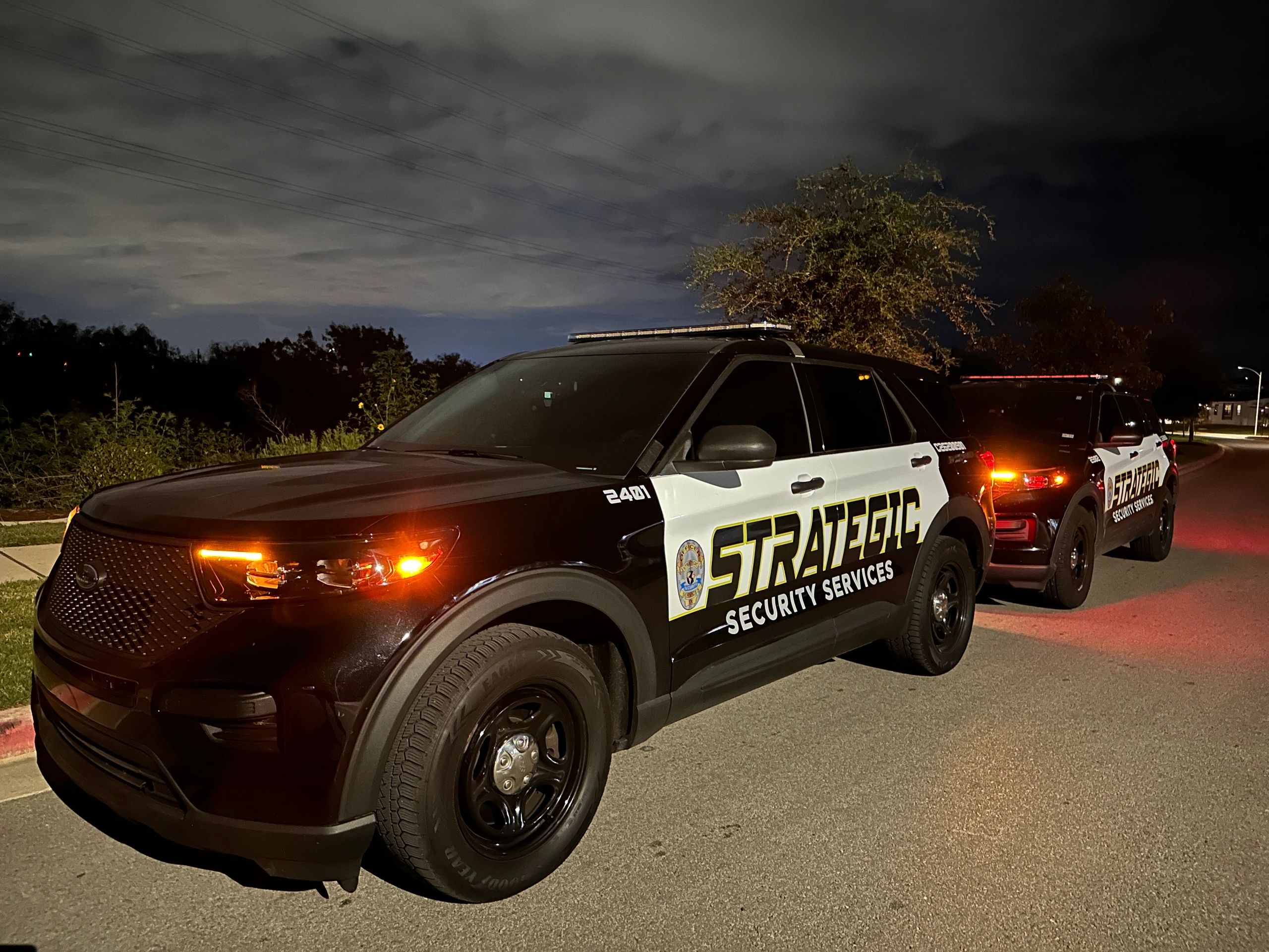 Two marked Strategic Security Services patrol vehicles staged at night.