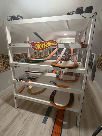 White shelf with Hot Wheels tracks and cars.