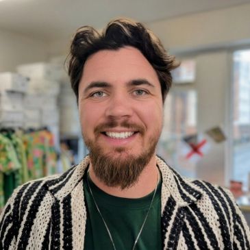 Smiling man with a beard indoors.