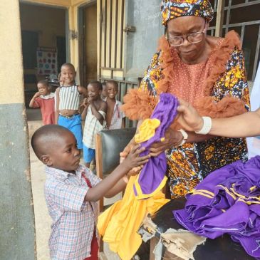 An elderly woman handing clothes to a boy with children watching.