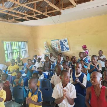 Children gathered in a classroom, clapping and interacting.