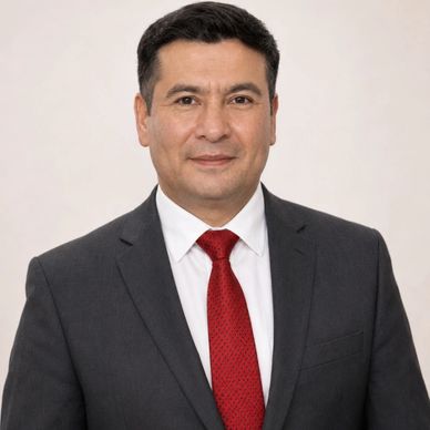 Professional man in dark suit and red tie against plain background.