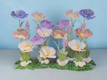 Delicate pastel-colored flowers arranged on a green base against a blue background.