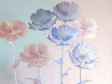 Delicate pastel flowers in soft pink and blue hues against a light background.