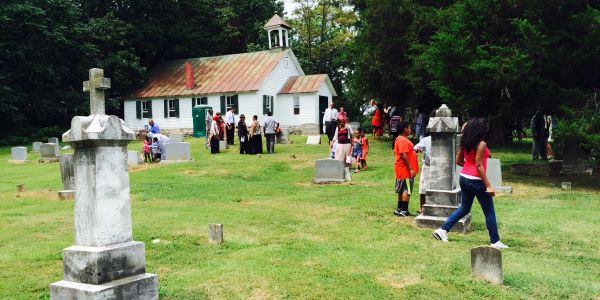 People gathered in a cemetery near a small church.