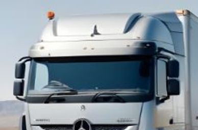 Silver Mercedes-Benz semi-truck driving on a highway in a desert area.