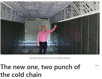 Man in a bright pink shirt stands inside an industrial container.