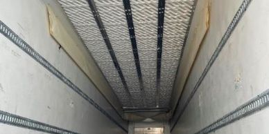 Empty interior of a large cargo truck or trailer with metal rails.