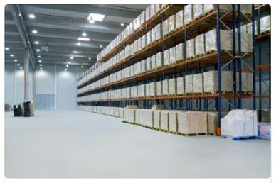 Large warehouse with stacked pallets on tall shelves and bright overhead lighting.