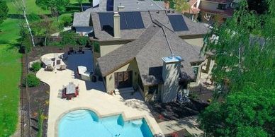 Aerial view of a modern house with a backyard pool and solar panels on the roof.