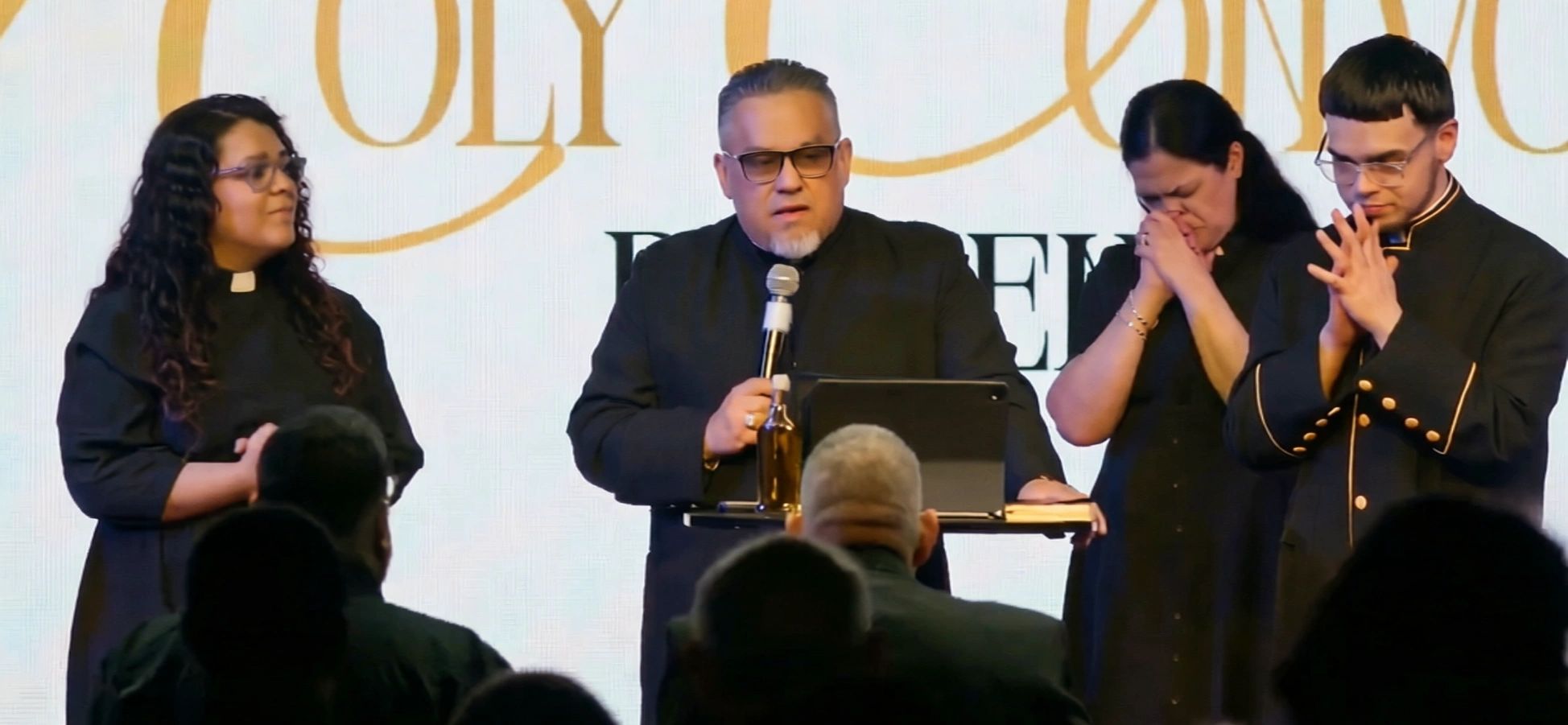 Four people on stage during a religious service.