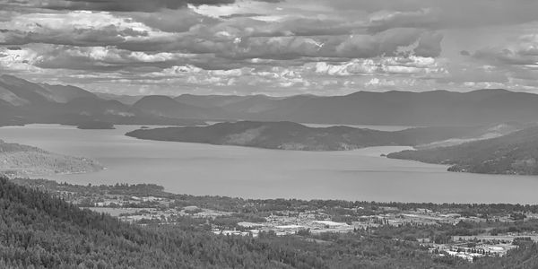Black and white scenic lake view with mountains and clouds.