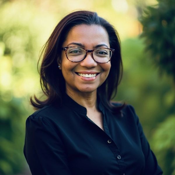Smiling woman with glasses outdoors.
