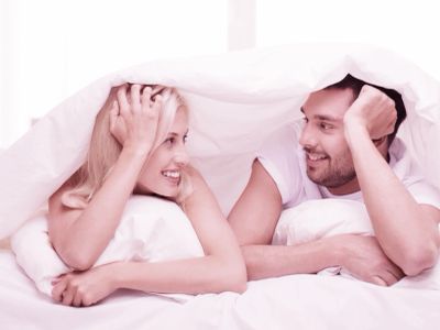 Couple smiling under blanket.