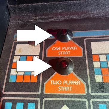 Close-up of an arcade game panel with one-player and two-player start buttons.