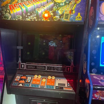 Vintage Atari Asteroids arcade game with colorful controls and screen.