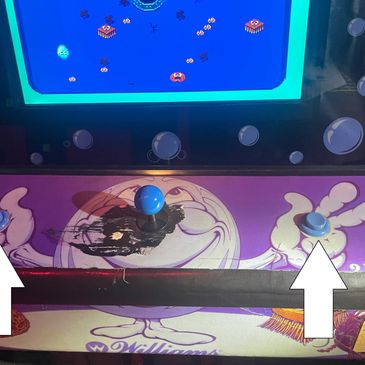 Close-up of a damaged arcade game joystick and button panel.
