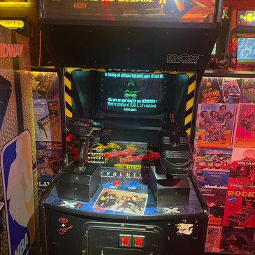 Retro arcade game machine with controllers and a game case on top.