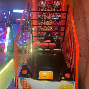 A basketball arcade game with neon lights and a digital scoreboard.