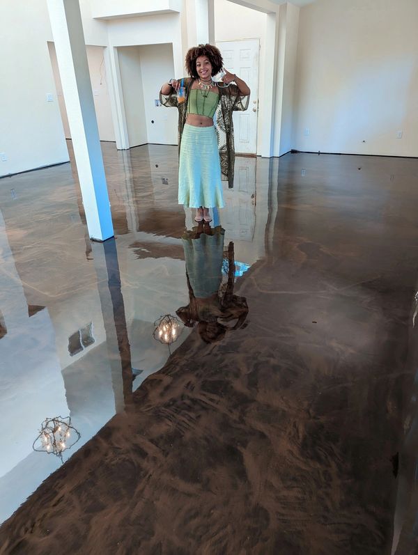 Woman standing barefoot on a shiny, freshly polished floor in an empty room.
