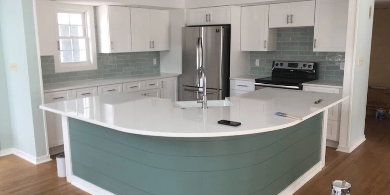 Modern kitchen with a white island and teal backsplash tiles.