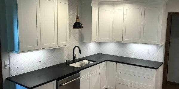 Modern kitchen with white cabinets and black countertops.