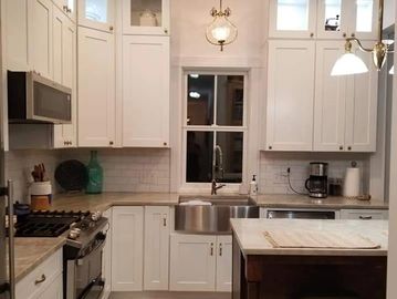Bright white kitchen with modern appliances and farmhouse sink.