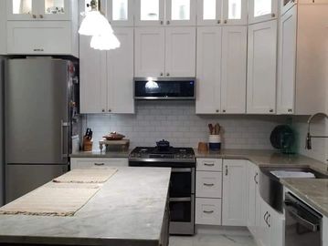 Modern kitchen with white cabinets and marble countertops.