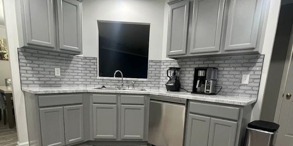 Modern kitchen with gray cabinets and stainless steel appliances.