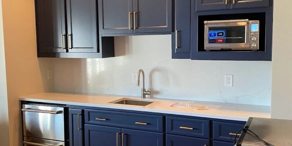 Modern kitchen with navy blue cabinets and stainless steel appliances.
