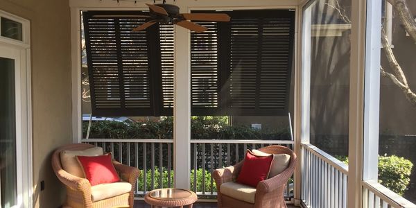 Screened porch makeover with fresh paint, stained floors, and decorative shutters.