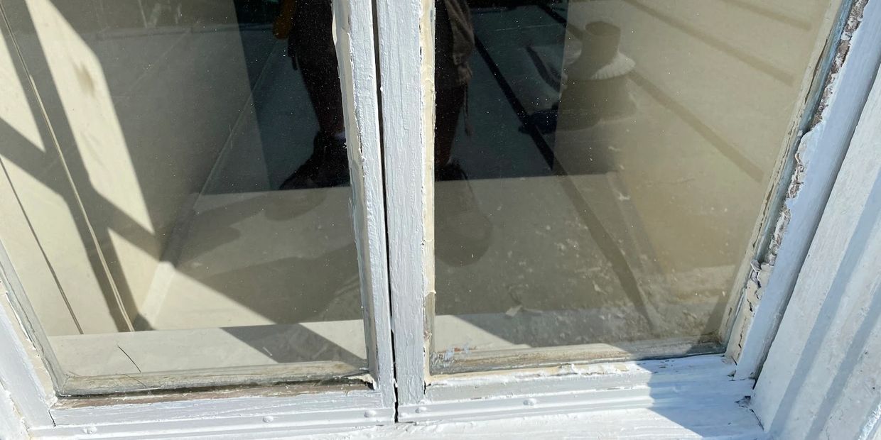 Close-up of a weathered window frame with peeling paint.