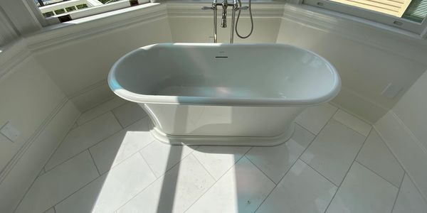 Luxury bathroom featuring a freestanding soaking tub, custom tile flooring, natural lighting, and pr