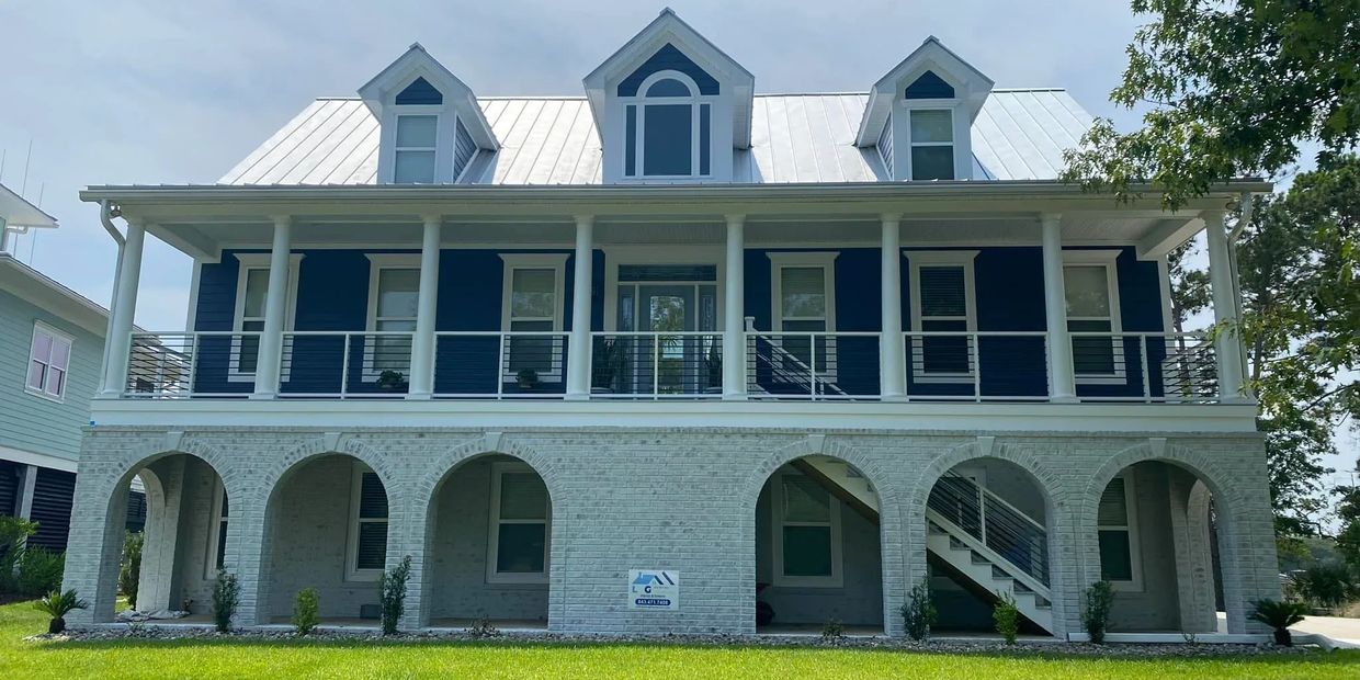 Charleston brick limewash project with white brick arches, blue siding, and a coastal porch.
