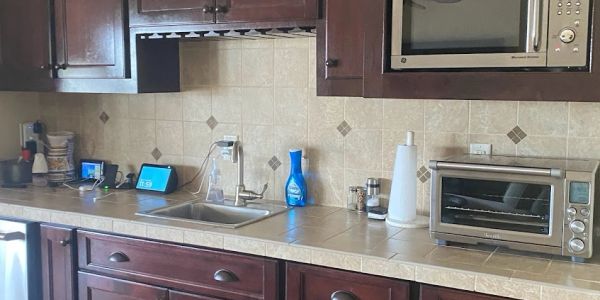 A tidy kitchen counter with dark wood cabinets, a sink, and various appliances.