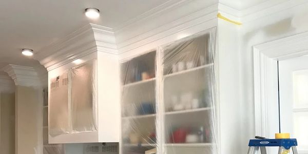 Kitchen cabinets and appliances covered for painting or renovation.