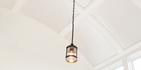 Hanging light fixture on a white ceiling near windows.