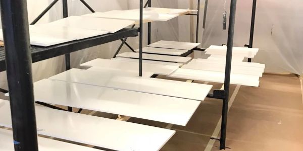 Shelves with white panels in a workspace under plastic sheets.