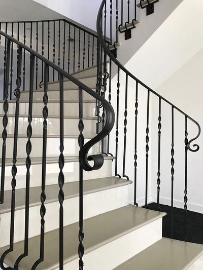 Elegant staircase with white steps and black wrought iron railing.