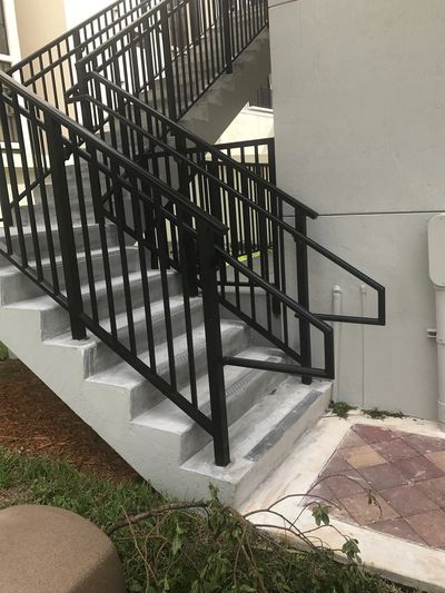 Concrete outdoor staircase with black metal railings beside a building.