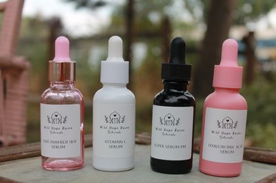 Four skincare serum bottles from Wild Hope Farms Naturals displayed outdoors.