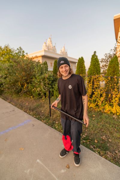 Young man in casual clothes holding a skateboard on a sunny day.