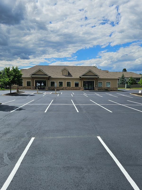 Empty parking lot in front of single-story office buildings on a partly cloudy day.