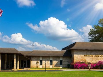 A small stone building under a bright blue sky with clouds.