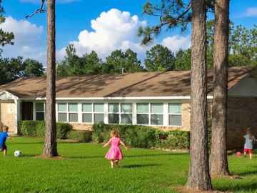 Three children playing outside near a house on a sunny day.