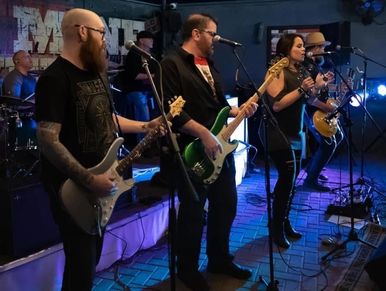 Band performing live on stage with guitars and microphones.