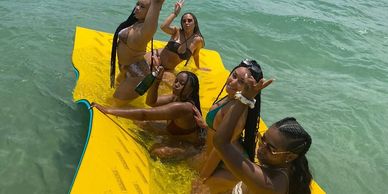 people on vacation floating on a water mat in the ocean in Miami FL