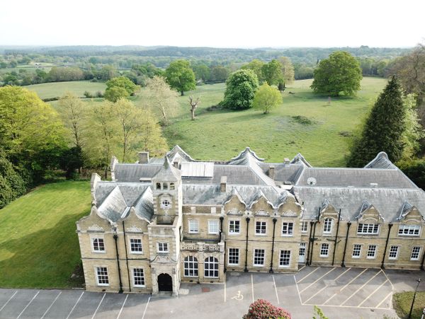 A large historic building surrounded by green fields and trees.