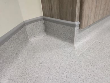 Clean floor corner with wall trim and wooden cabinet.